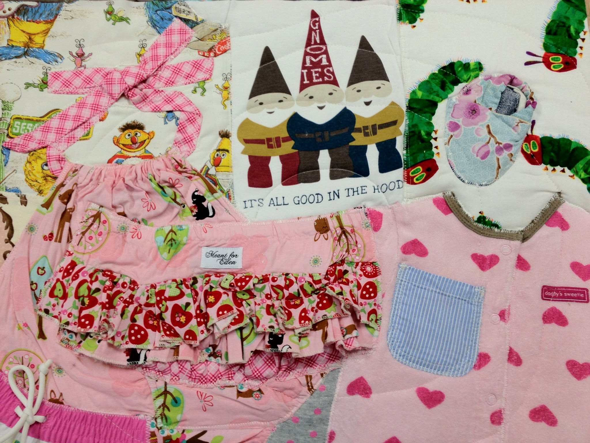 A pile of a child's outgrown baby clothes before becoming a quilt.